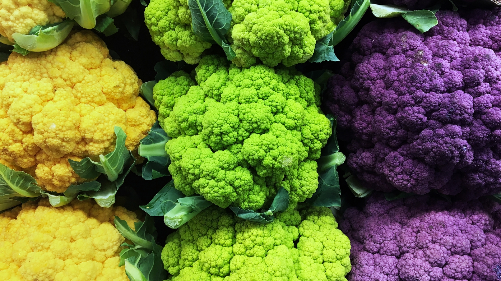 A still-life of yellow, green, and purple cauliflower.